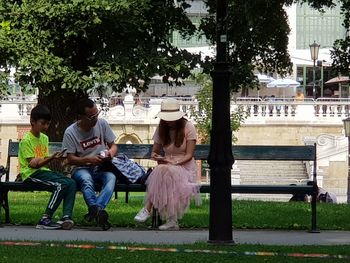 People sitting on bench against plants