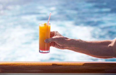 Cropped hand of man having drink on boat in sea