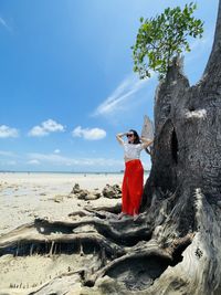 Rear view of woman standing at beach against sky