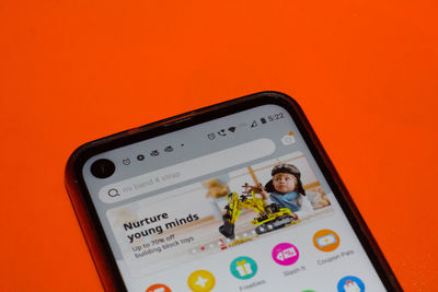 Close-up of smart phone against orange background