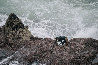 High angle view of man standing on rock in sea