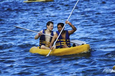 Male friends kayaking on sea