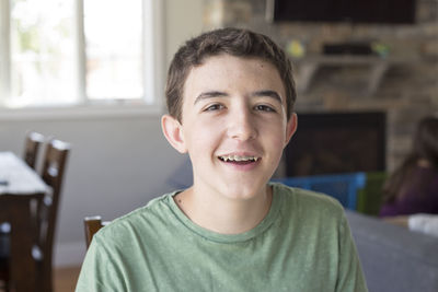 Close-up portrait of teenage boy with braces at home
