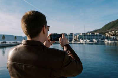 Young man photographing against sky