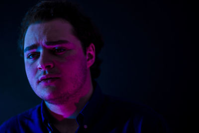 Close-up of man looking away against black background