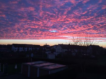 Houses against cloudy sky at sunset