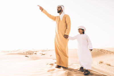 Men standing on sand against sky