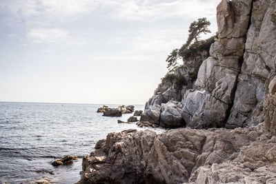 Rock formation on beach against sky