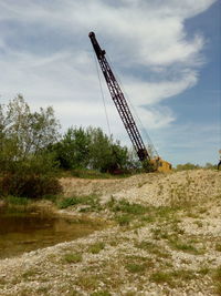 Low angle view of crane at construction site against sky