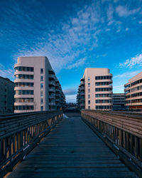 Footpath amidst buildings in city against sky