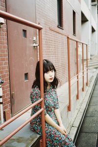 Portrait of woman standing against railing