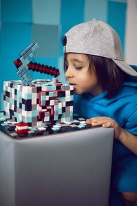 Boy in blue clothes bites at a cake pixels with a pickaxe in the studio. birthday five years