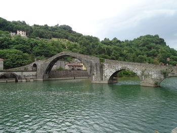 Arch bridge over river against sky