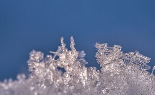 Low angle view of frozen lake against clear blue sky