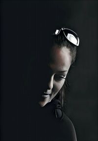 Portrait of woman wearing sunglasses against black background