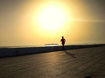 Silhouette man standing on beach against clear sky during sunset