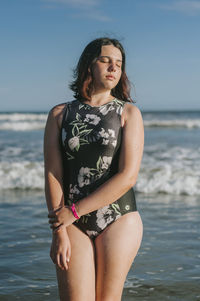 Beautiful woman standing at beach against sky