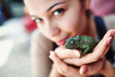 Close-up of young woman holding chameleon