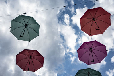 Low angle view of umbrellas hanging against sky