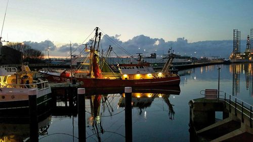 Boats moored at harbor against sky in city