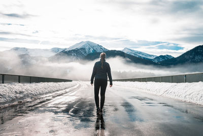 Rear view of man on snowcapped mountain against sky