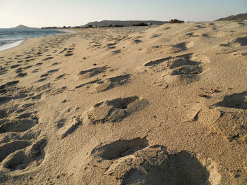 Footprints on sand at beach against sky