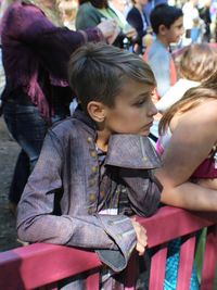 Thoughtful boy standing by railing in city during event