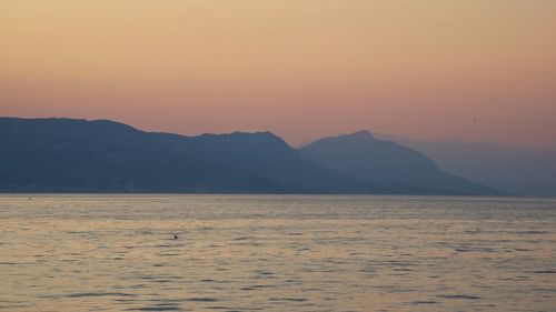 Scenic view of sea and mountains against clear sky