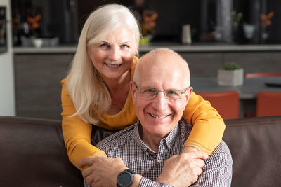 Portrait of smiling senior couple sitting at home