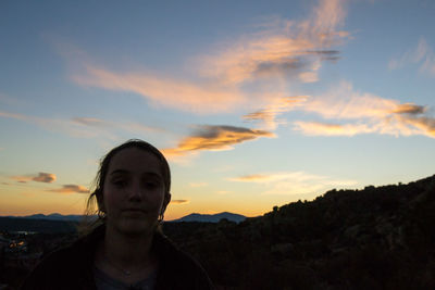 Portrait of teenage girl standing against sky during sunset