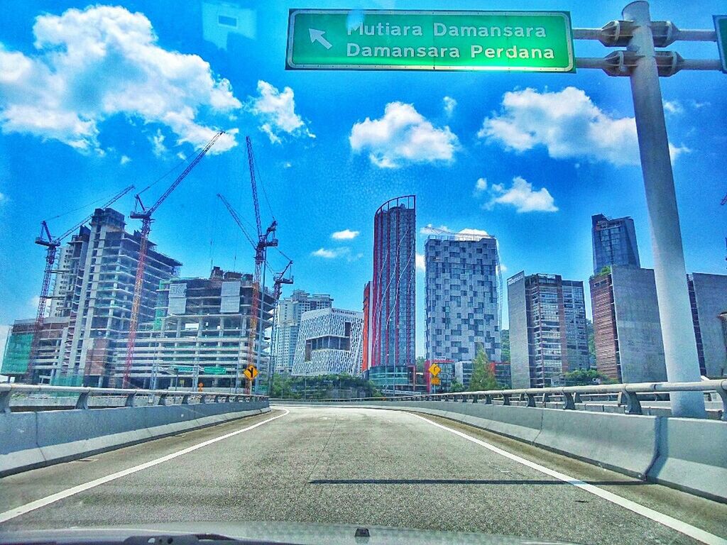 building exterior, architecture, built structure, city, sky, transportation, road, street, the way forward, car, cloud - sky, cloud, road marking, road sign, diminishing perspective, street light, communication, city life, day, building