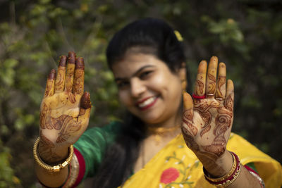 Indian woman with smiling face showing palms painted with mahendi or myrtle