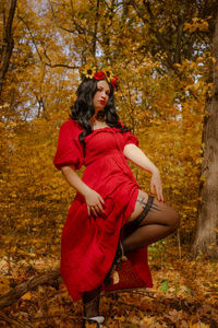 Portrait of young woman sitting on tree trunk