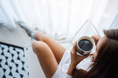 Midsection of woman holding coffee cup at home