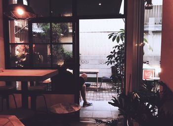 Rear view of man sitting by doorway at restaurant