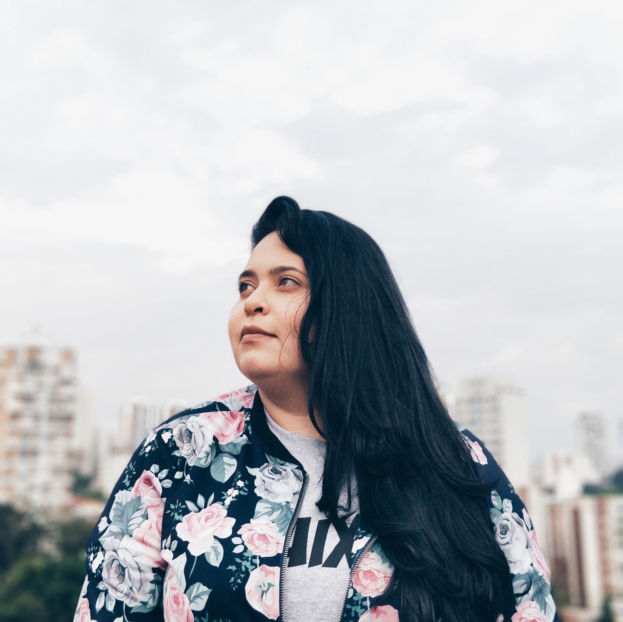 one person, real people, lifestyles, sky, leisure activity, standing, focus on foreground, black hair, building exterior, young adult, architecture, hair, long hair, casual clothing, built structure, looking away, looking, young women, front view, hairstyle, outdoors, beautiful woman, contemplation, floral pattern