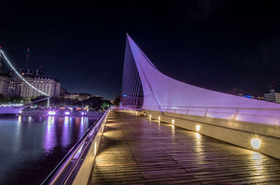 Illuminated bridge over river at night