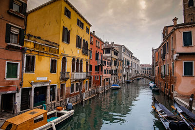 Canal amidst buildings in city against sky