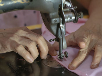 Close-up of woman sewing textile using machine