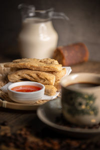 Keropok lekor or fried fish cake on a rattan plate with a sweet chilli sauce and on wooden table. 