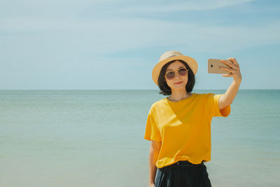 Woman taking selfie from phone against sea