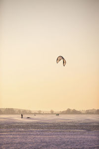 Germany, brandenburg, rangsdorf, winter landscape with frozen lake, people playing with kite