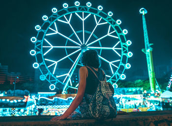 Rear view of woman in amusement park ride at night