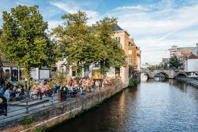 People at outdoor cafe by canal in city