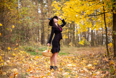 Full length of young woman standing in forest