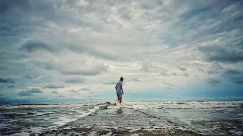 Man standing in sea against sky