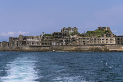 Buildings at waterfront against blue sky