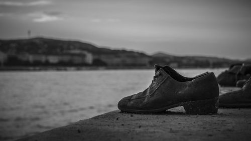 Shoes on riverbank against sky