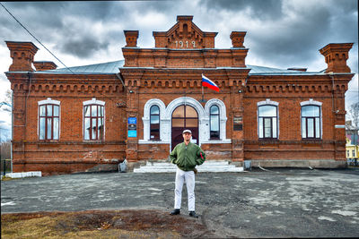 Rear view of man standing by building against sky