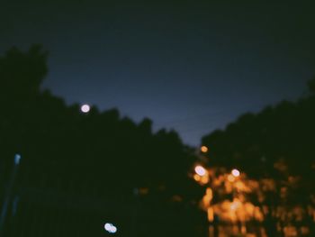 Defocused image of illuminated city against sky at night